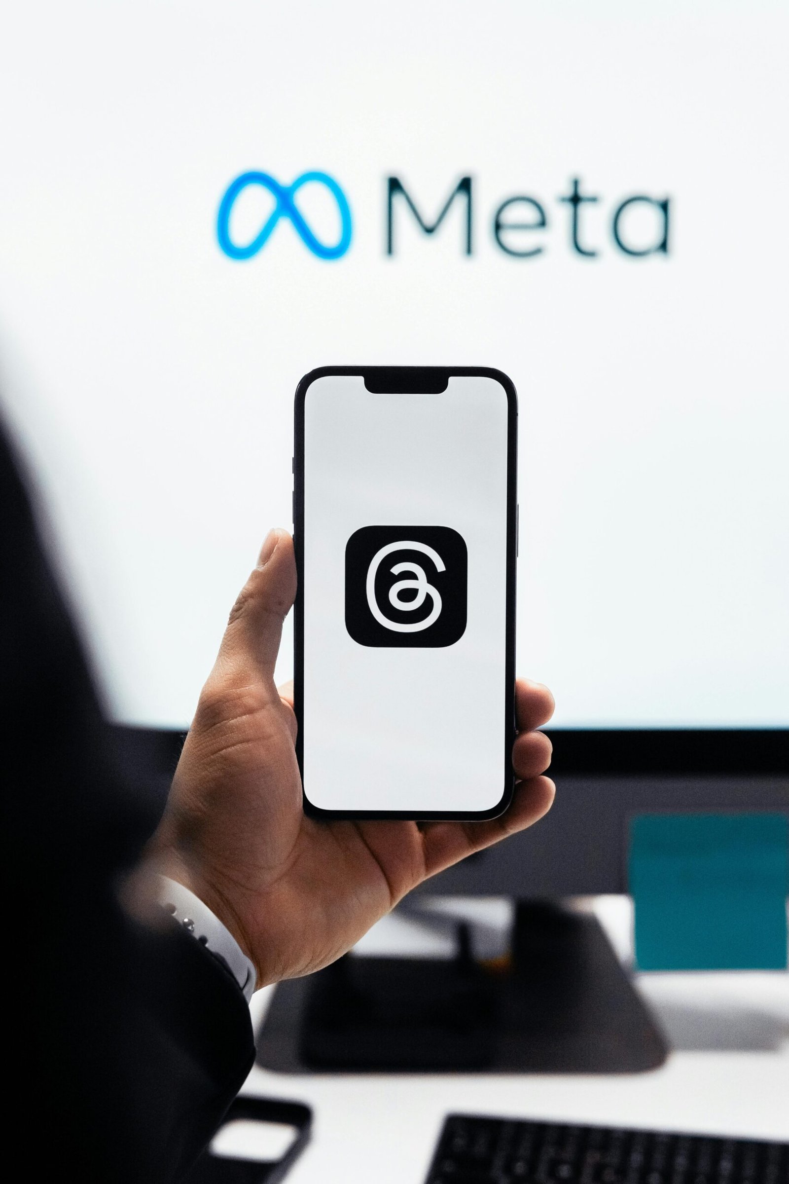 Close-up of a person holding a smartphone displaying Meta's threads logo.